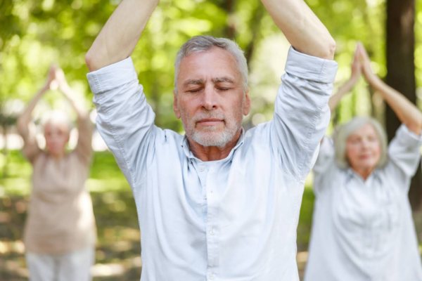 A group of people practicing tai chi in a park to promote body awareness.