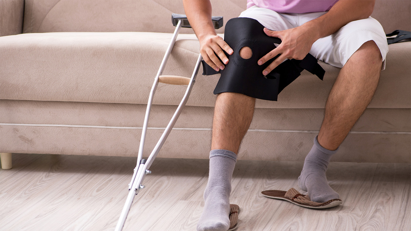 A person putting on their knee brace post-surgery.