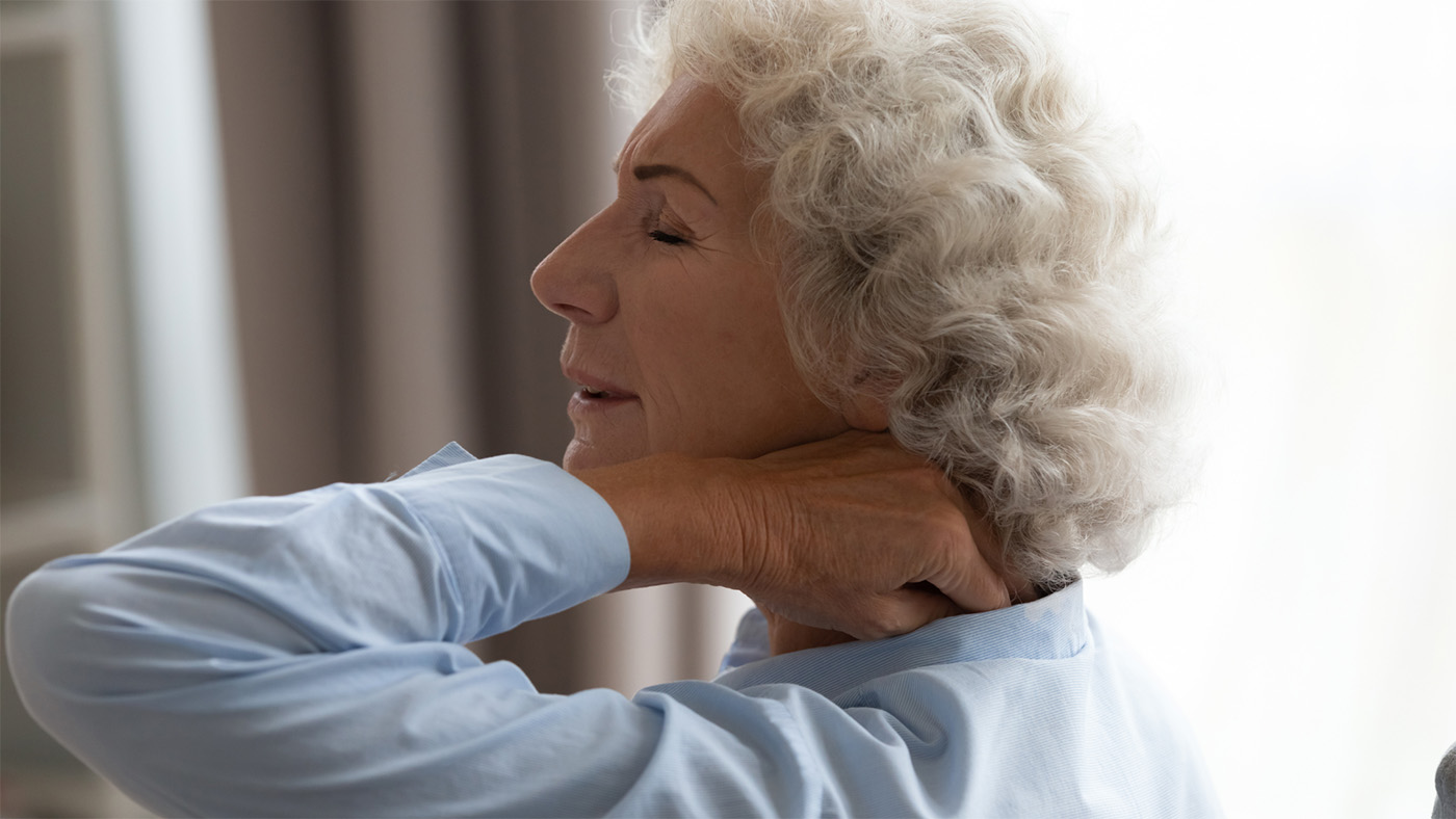 An older woman holding her sore neck.