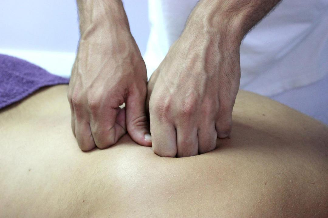 A massage therapist's hand giving a back massage to a patient.