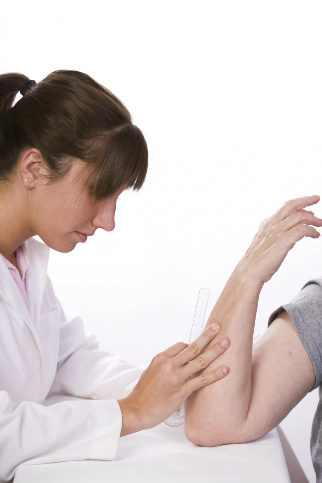 physical therapist measures the range of motion in an elbow with a goiniometer