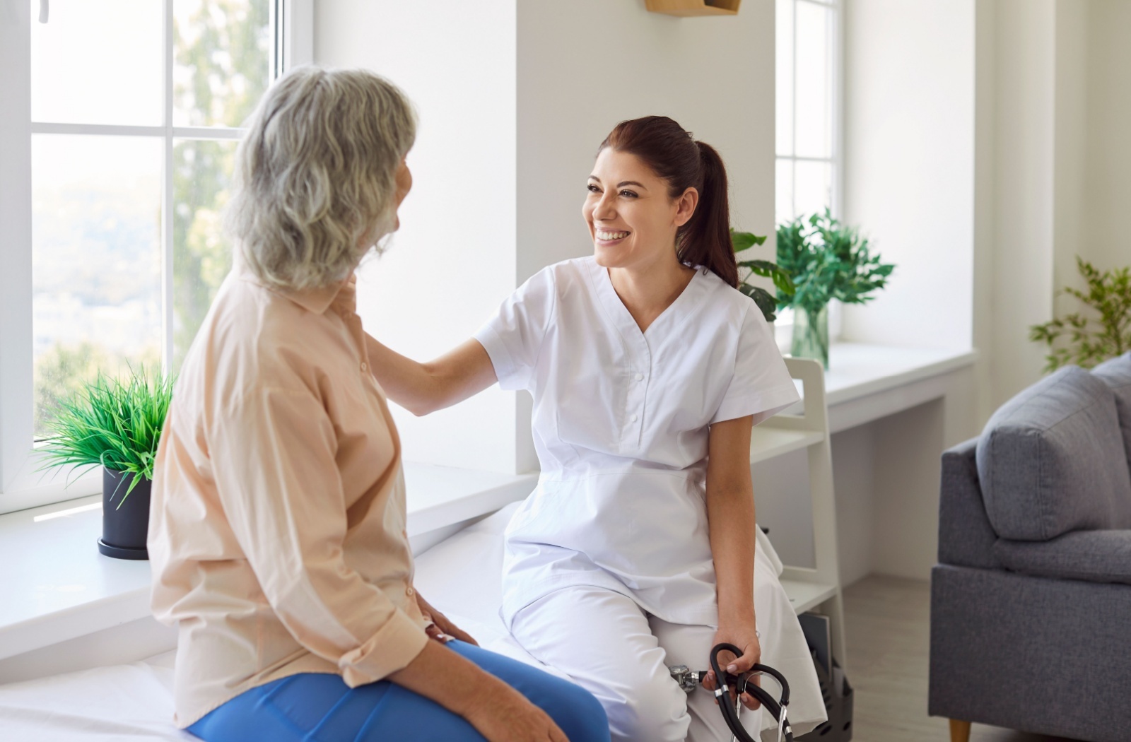 Smiling nurse comforting older adult patient during a clinic visit