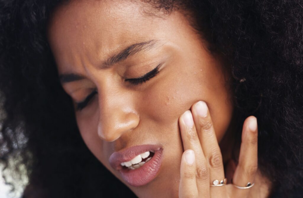 Close-up of person pressing their jaw with visible tension and discomfort suggesting TMJ-related pain